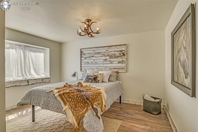 bedroom with wood finished floors, baseboards, and a chandelier