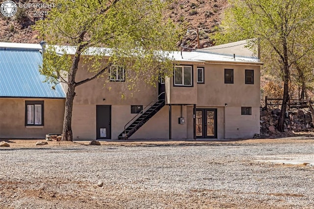 view of front of house featuring stairs, french doors, and stucco siding