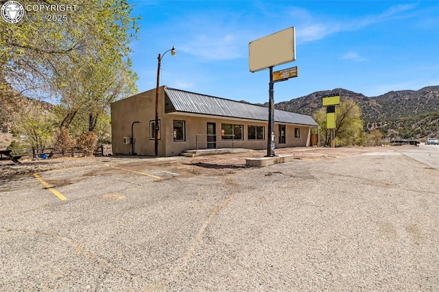 view of front of house featuring stucco siding, uncovered parking, a mountain view, and metal roof