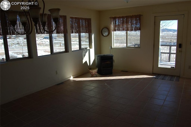 interior space featuring dark tile patterned flooring, a wealth of natural light, and a wood stove