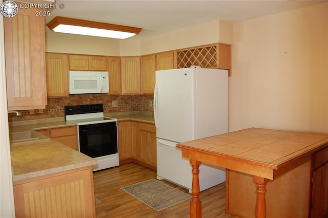 kitchen featuring sink, light brown cabinets, light wood-type flooring, kitchen peninsula, and white appliances