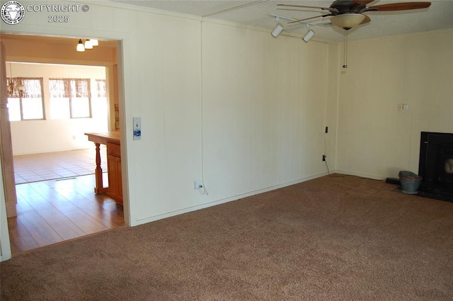 unfurnished living room with rail lighting, ceiling fan, and carpet