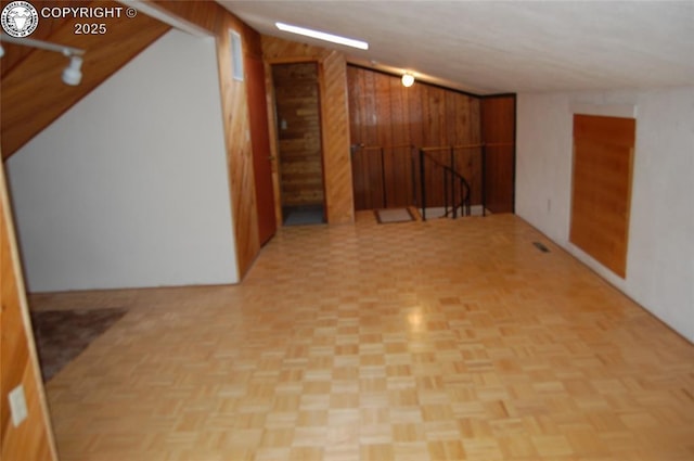 basement with light parquet floors and wood walls