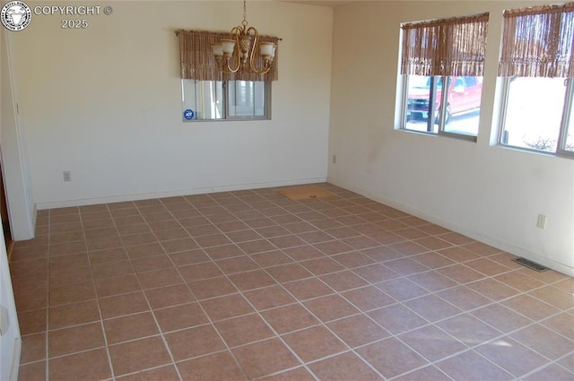 tiled empty room featuring a notable chandelier