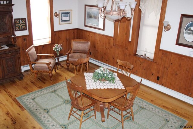 living area with hardwood / wood-style flooring, an inviting chandelier, and a baseboard heating unit