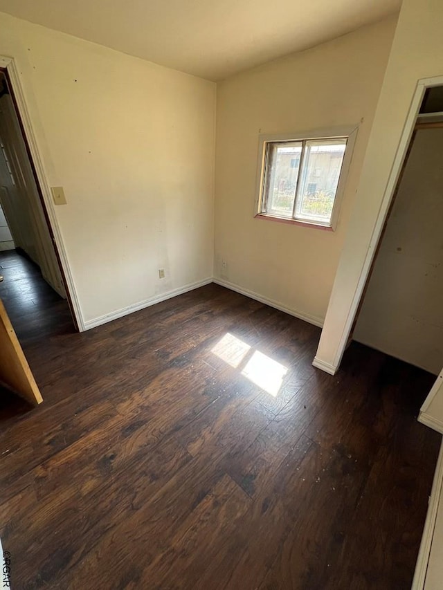 unfurnished bedroom with dark hardwood / wood-style floors and a closet