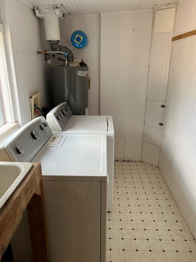 clothes washing area featuring wooden walls, washing machine and dryer, and gas water heater