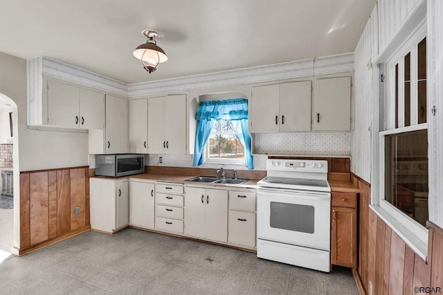 kitchen with electric stove, sink, backsplash, and white cabinets