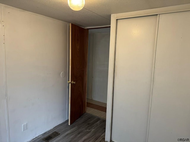 unfurnished bedroom featuring dark hardwood / wood-style floors, a closet, and a textured ceiling