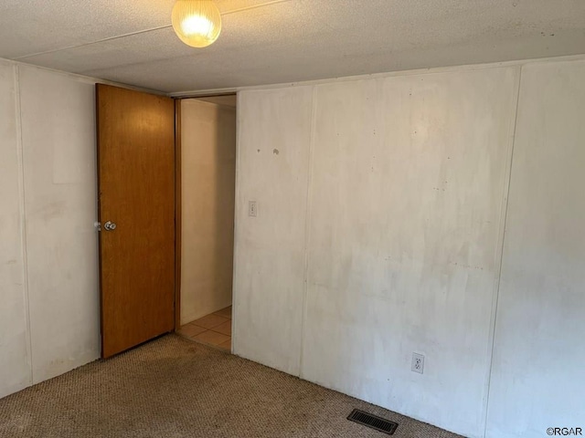 spare room featuring light carpet and a textured ceiling