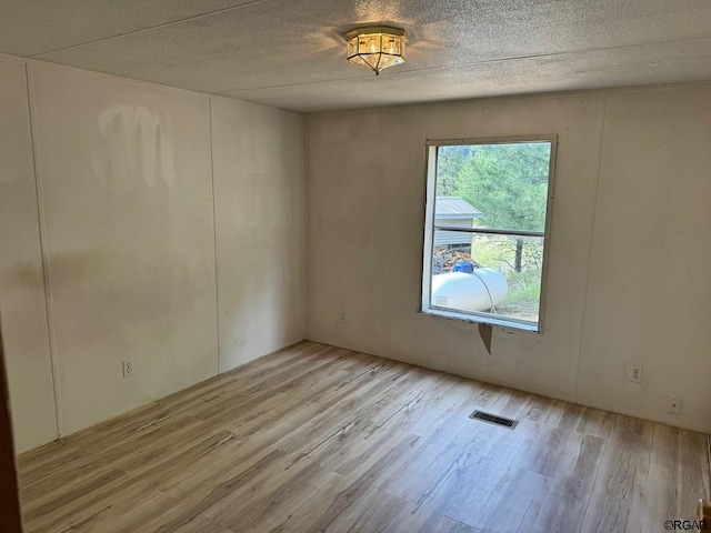 unfurnished room featuring light hardwood / wood-style flooring and a textured ceiling