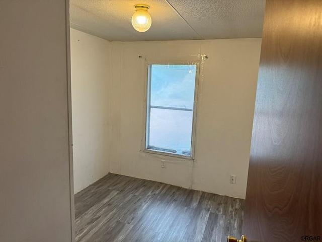 unfurnished room featuring dark hardwood / wood-style floors and a textured ceiling