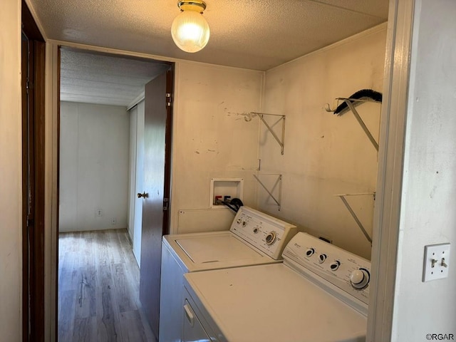 laundry area with wood-type flooring, washing machine and dryer, and a textured ceiling