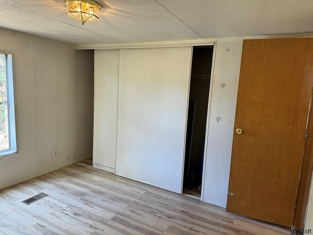 unfurnished bedroom with a closet, a textured ceiling, and light hardwood / wood-style flooring