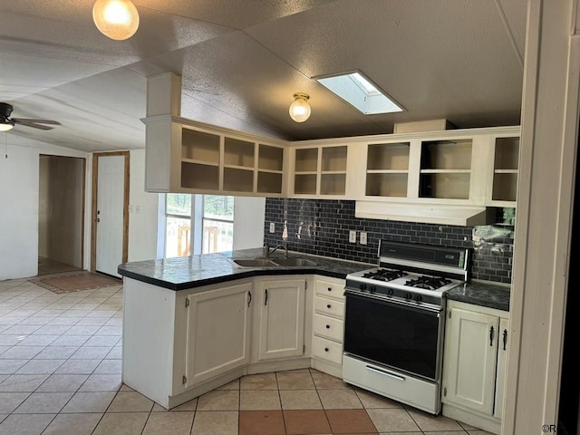 kitchen with vaulted ceiling, white cabinets, light tile patterned floors, kitchen peninsula, and white gas stove