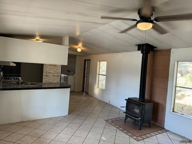 kitchen featuring washer and dryer, white cabinetry, sink, and a wood stove