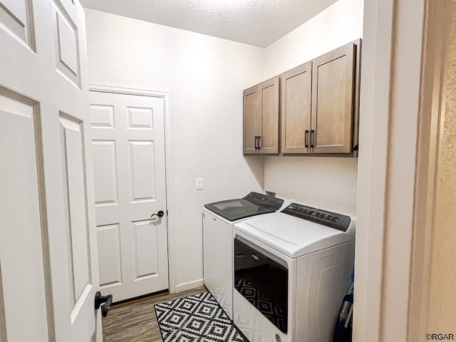 clothes washing area with cabinets, independent washer and dryer, wood-type flooring, and a textured ceiling