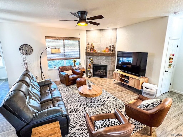 living room with hardwood / wood-style flooring, ceiling fan, a fireplace, and a textured ceiling