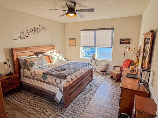 bedroom featuring dark wood-type flooring, a textured ceiling, and ceiling fan