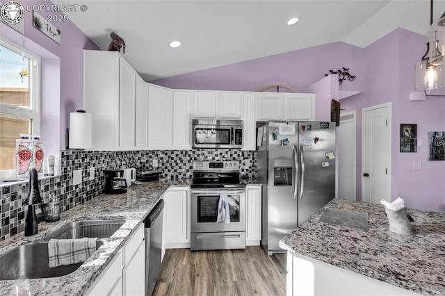 202 First St, Silver Cliff, CO 81252 - kitchen featuring appliances with stainless steel finishes, vaulted ceiling, white cabinets, light wood-style floors, and decorative backsplash