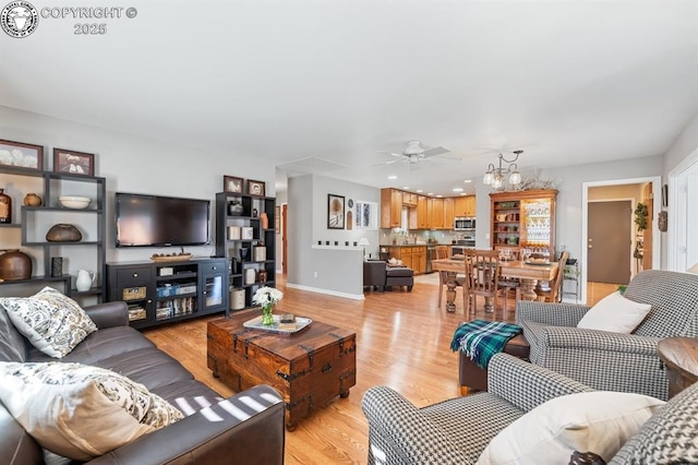 living area with light wood-type flooring, baseboards, and a ceiling fan