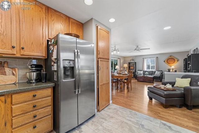 kitchen featuring open floor plan, tasteful backsplash, a ceiling fan, and stainless steel fridge