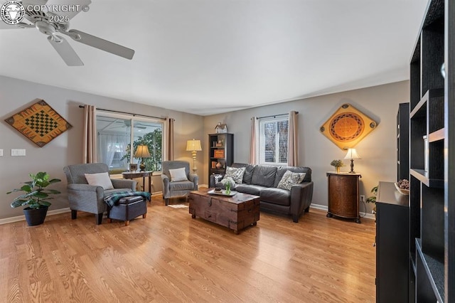 living area featuring light wood finished floors, a ceiling fan, and baseboards