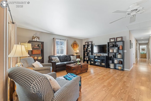 living area featuring light wood-type flooring, baseboards, and ceiling fan