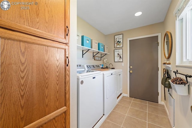 clothes washing area featuring washer and clothes dryer, light tile patterned floors, and cabinet space