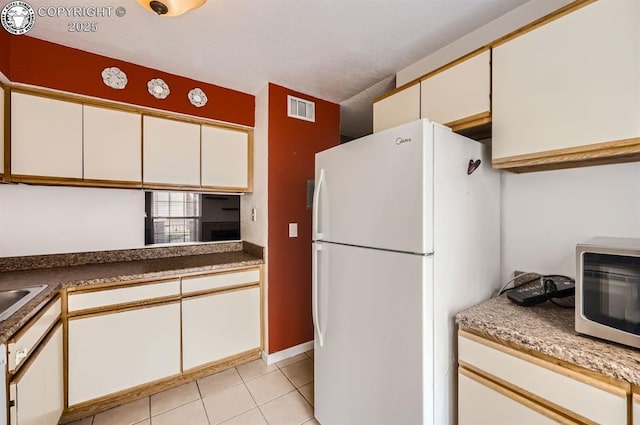 3210 Van Teylingen Dr, Colorado Springs, CO 80917 - kitchen featuring freestanding refrigerator, stainless steel microwave, light tile patterned floors, white cabinets, and a sink