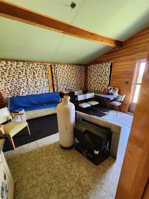 interior space with vaulted ceiling with beams and wooden walls