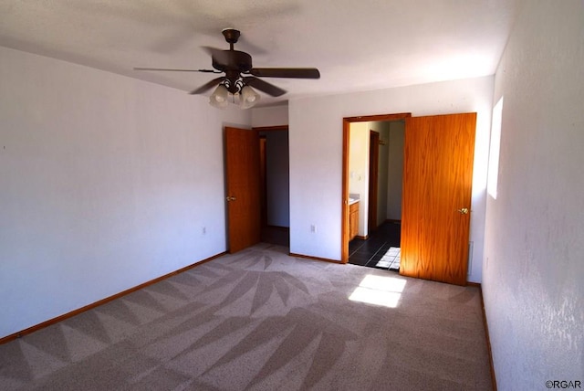 unfurnished bedroom featuring connected bathroom, dark carpet, and ceiling fan