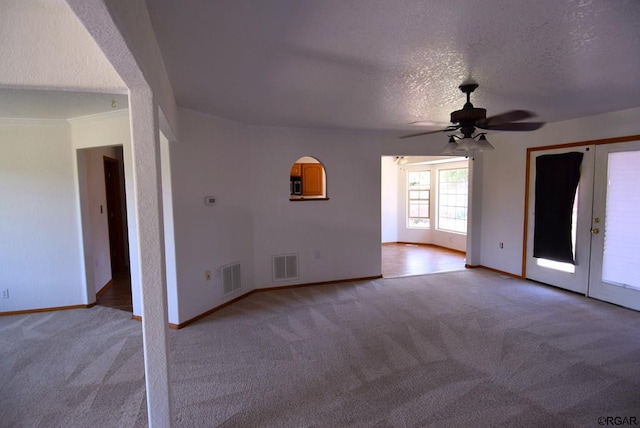 carpeted empty room featuring ceiling fan, a textured ceiling, and french doors