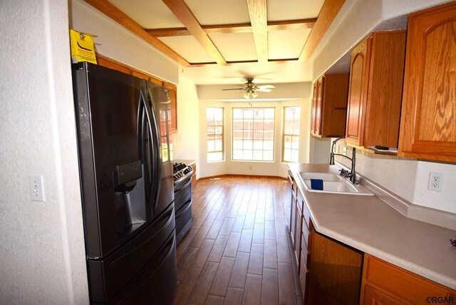 kitchen featuring sink, coffered ceiling, stainless steel gas range oven, black fridge, and light hardwood / wood-style flooring