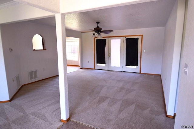 empty room featuring ceiling fan, light colored carpet, and a textured ceiling