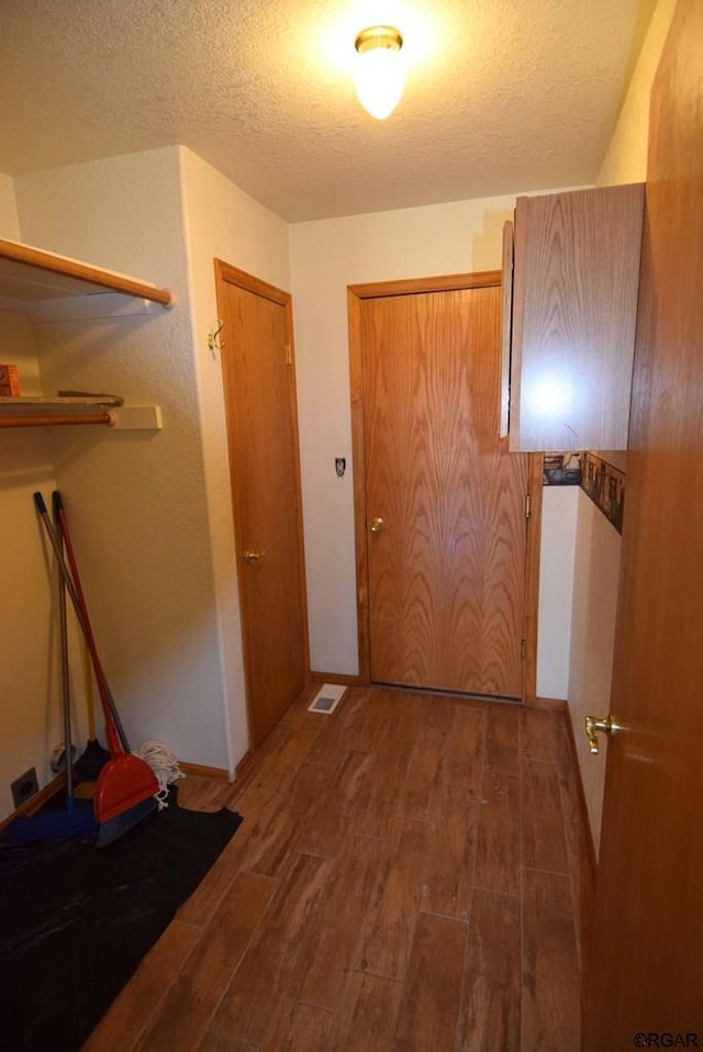 corridor with dark wood-type flooring and a textured ceiling