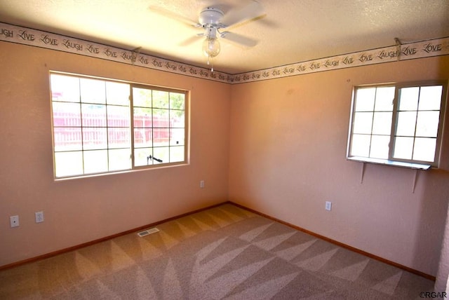 carpeted empty room with ceiling fan and a textured ceiling