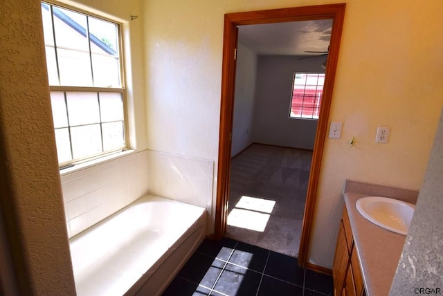 bathroom featuring tile patterned flooring, vanity, a tub, and ceiling fan