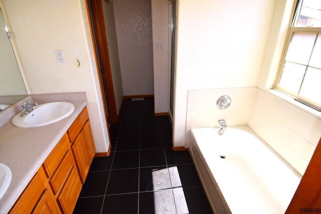 bathroom featuring tile patterned flooring, a tub to relax in, and vanity