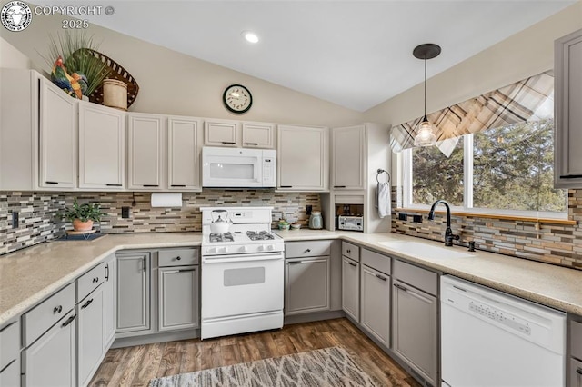 kitchen featuring white appliances, wood finished floors, lofted ceiling, a sink, and light countertops