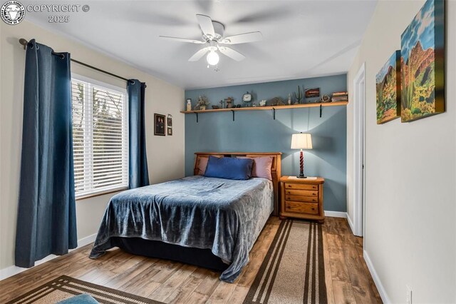 bedroom with baseboards, wood finished floors, and a ceiling fan