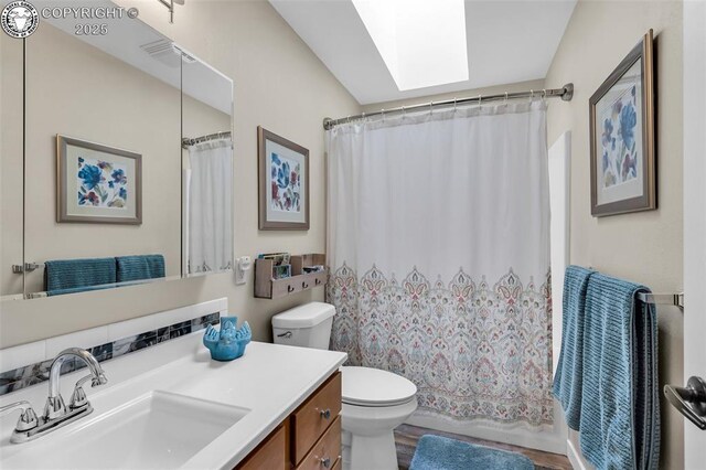 bathroom with toilet, curtained shower, a skylight, and vanity