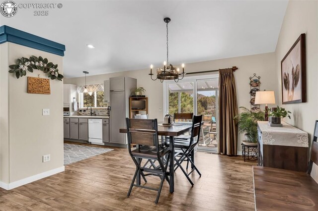 dining room featuring a notable chandelier, light wood-style floors, baseboards, and a wealth of natural light