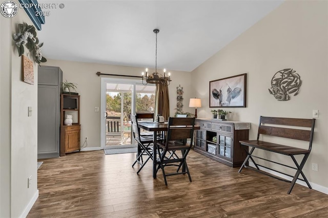 dining area featuring dark wood finished floors, vaulted ceiling, a notable chandelier, and baseboards