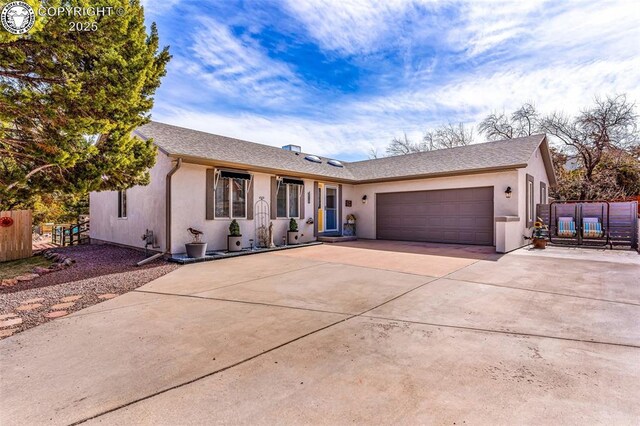 ranch-style house with fence, a garage, driveway, and stucco siding