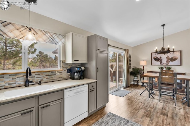 kitchen with gray cabinetry, a sink, backsplash, dishwasher, and vaulted ceiling