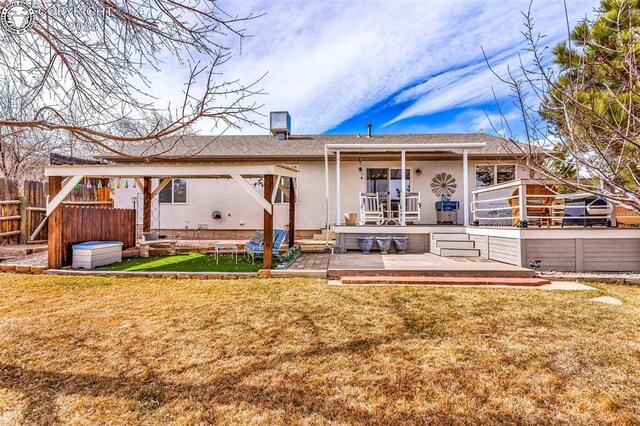 back of house with stucco siding, a patio, a lawn, and fence