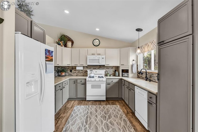 kitchen with a sink, white appliances, gray cabinets, and vaulted ceiling