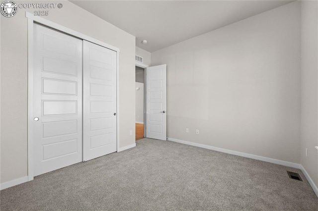 unfurnished bedroom featuring carpet floors, baseboards, visible vents, and a closet