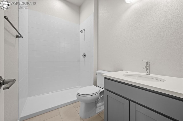 full bathroom featuring a textured wall, toilet, a tile shower, vanity, and tile patterned floors